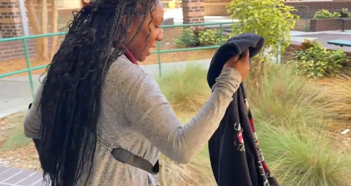 JHop administrator Dominique Dudley holds up a hooded sweatshirt collected from a student during  a recent sweep. School leaders are cracking down on students who violate the dress code by wearing the popular “hoodies”. 