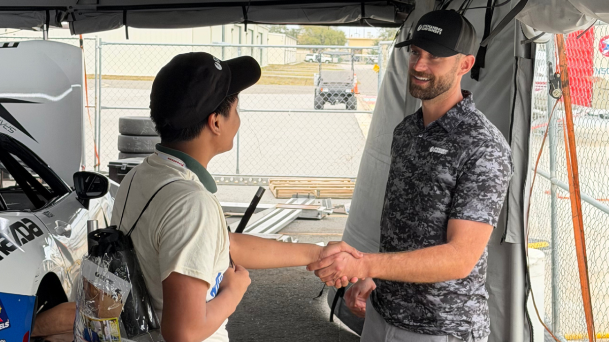 Trojan eighth-grader Omar Boyle shakes hands with Mazda Series driver Ryan Leach.