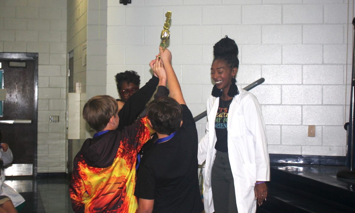 Students from Lealman Avenue Elementary raise their trophy in victory after receiving it from event host Dr. Destanee Cunningham. 